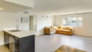 A modern kitchen with a built-in island, a dining area with a wooden table, and a living space with a sofa and a window. - Community Pool: Scottsdale Condo 2 Mi to ASU (Scottsdale)