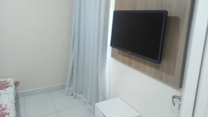 A bathroom with a shower curtain, a mounted television, a toilet, and a sink. - Ground floor apartment, in the VG Sun condominium. Condominium right on the sand. (Caucaia)