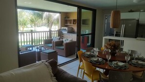 A dining area with a table set for four, a sofa, and a view of a patio with outdoor furniture. - Ground floor apartment, in the VG Sun condominium. Condominium right on the sand. (Caucaia)