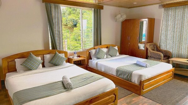 A hotel room with two single beds, a wooden wardrobe, a chair, and a small table.