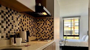 A modern kitchen with checkered tile backsplash, a built-in stove, and a window overlooking a cityscape. - w Radiant 1BR in Santa Barbara (Bogotá)