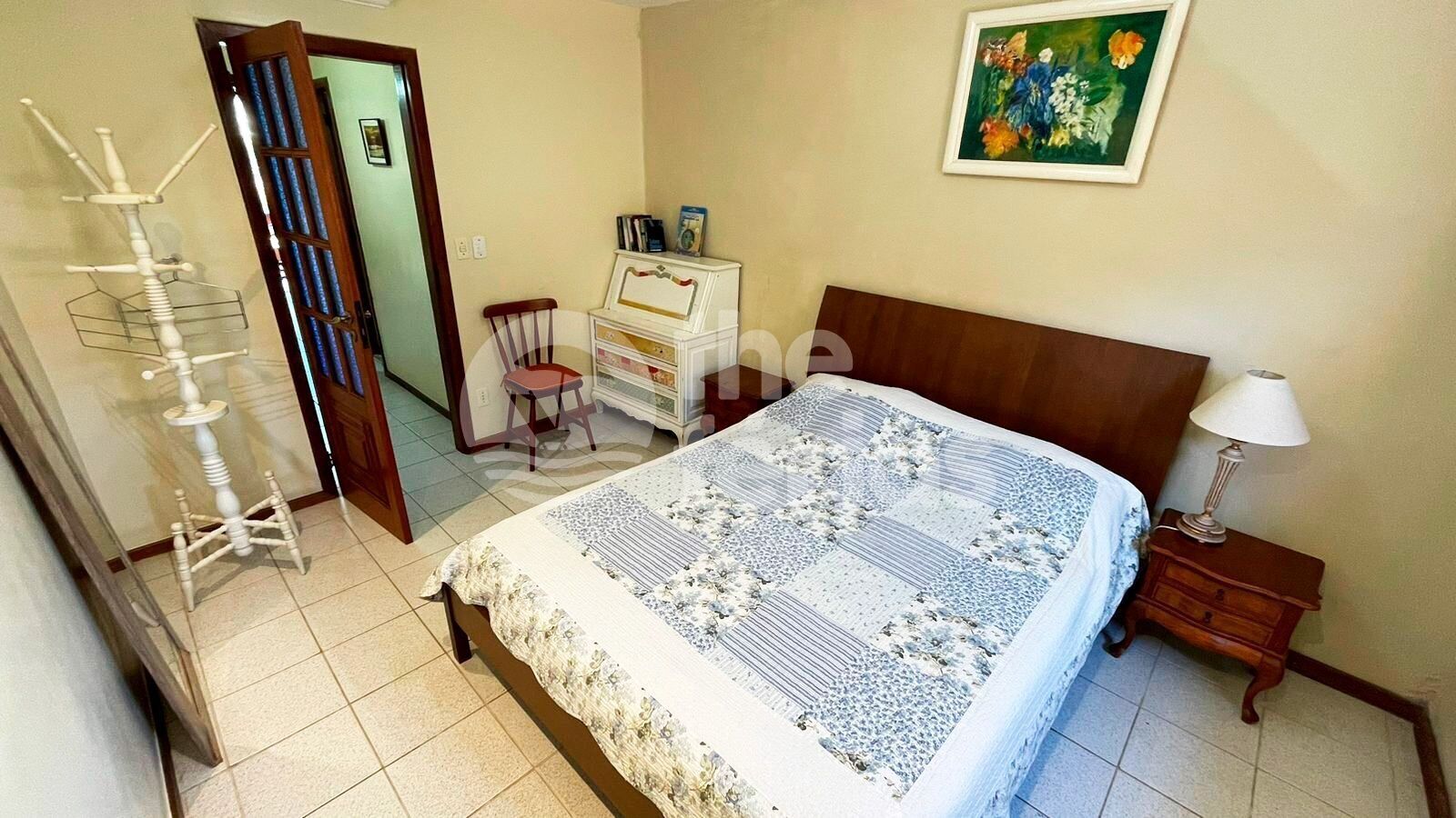 A bedroom with a bed, a dresser, a chair, a lamp, and a painting on the wall.