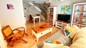 A living room with a sofa, a coffee table, a TV stand, and a dining area with a table and chairs. - House with private garden, BBQ community pool and WiFi (Mont-roig del Camp)