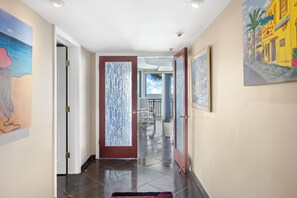 A hallway with a tiled floor, a door with frosted glass panels, and artwork on the walls.