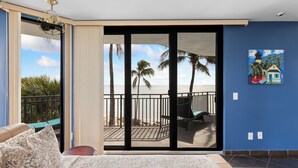A bedroom with a large sliding glass door leading to a balcony with a view of the beach and palm trees. - Oceanfront Luxury Panoramic Views & Designer Finishes Key West Beach location (Key West)