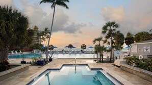 A pool area with lounge chairs and umbrellas, palm trees, and a view of the beach. - Oceanfront Luxury Panoramic Views & Designer Finishes Key West Beach location (Key West)