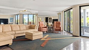 A spacious living room with a large sectional sofa, leather armchairs, and a dining area with a glass table. - Oceanfront Luxury Panoramic Views & Designer Finishes Key West Beach location (Key West)
