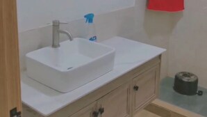 A bathroom with a white sink, a mirror, and a red towel hanging on the wall. - Furnished studio in DAKAR quiet in a building with security and comfort assured (Dakar)