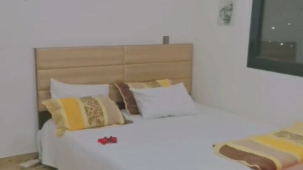 A neatly made bed with a wooden headboard, white bedding, and a few decorative pillows. - Furnished studio in DAKAR quiet in a building with security and comfort assured (Dakar)