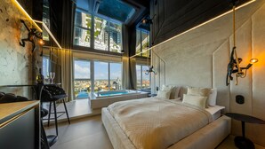 A modern bedroom with a large bed, a view of the city, a desk, and a bathtub. - Quorum Apartments (Wroclaw)
