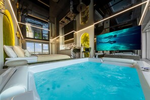 A modern interior with a large indoor pool, a seating area with a view, and a large flat-screen TV. - Quorum Apartments (Wroclaw)