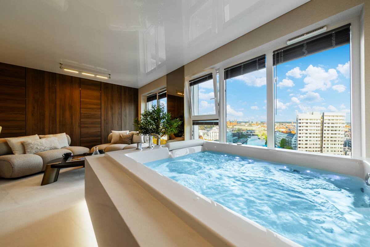 Ein modernes Interieur mit einer großen Badewanne, einem Sofa und Blick auf die Stadt.
