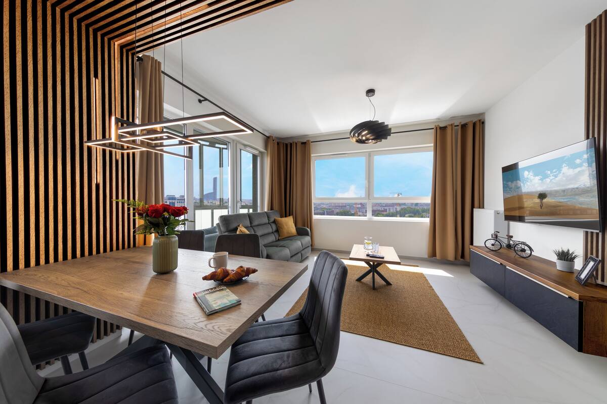 Ein modernes Wohnzimmer mit Essbereich, großen Fenstern und Blick auf die Stadt.