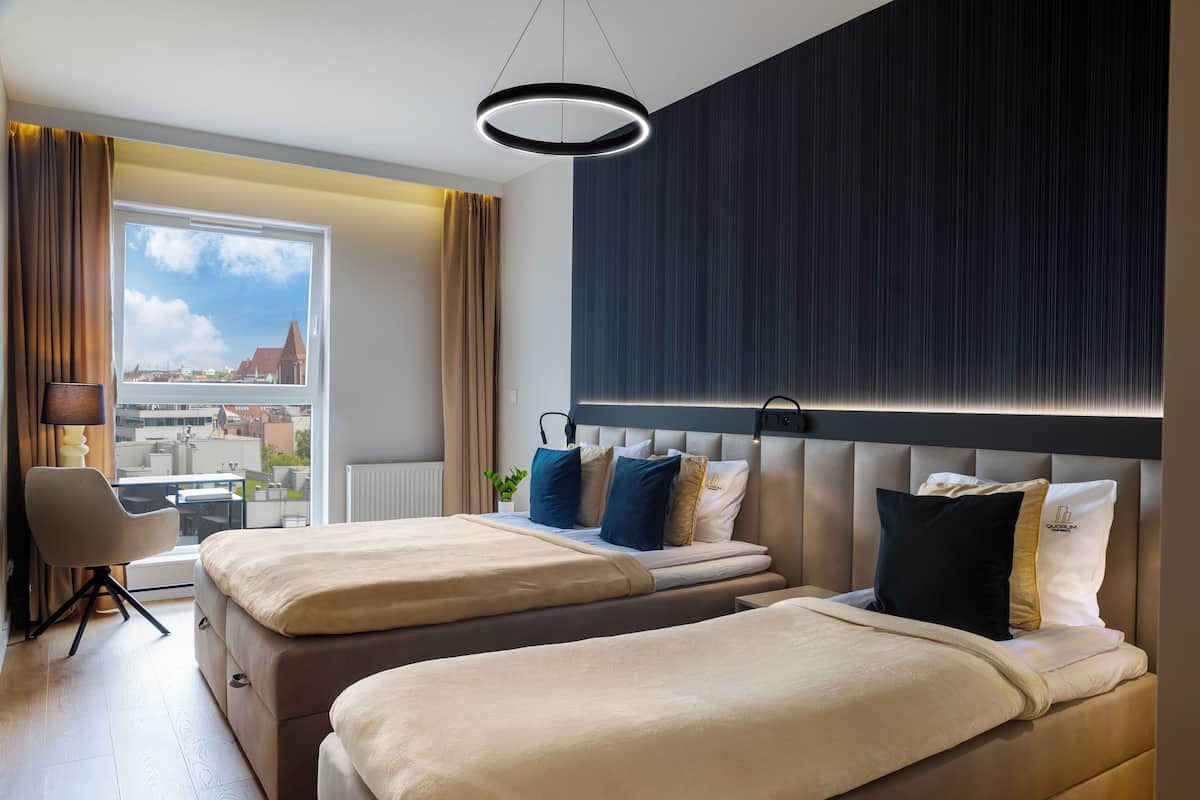 Ein Hotelzimmer mit zwei Betten, einem Schreibtisch und Blick auf die Stadt.