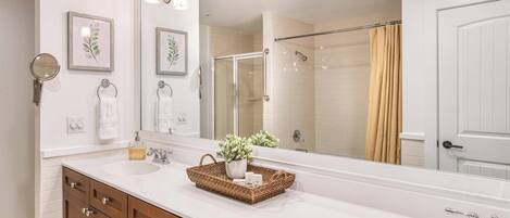A modern bathroom with two sinks, a large mirror, and a shower.