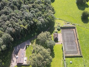An aerial view of a property with a tennis court, a small building, and surrounding greenery. - The Old Workshop (Corbridge)