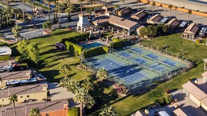 Vue aérienne d’un complexe hôtelier doté de plusieurs courts de tennis, de palmiers et situé en bord de mer.