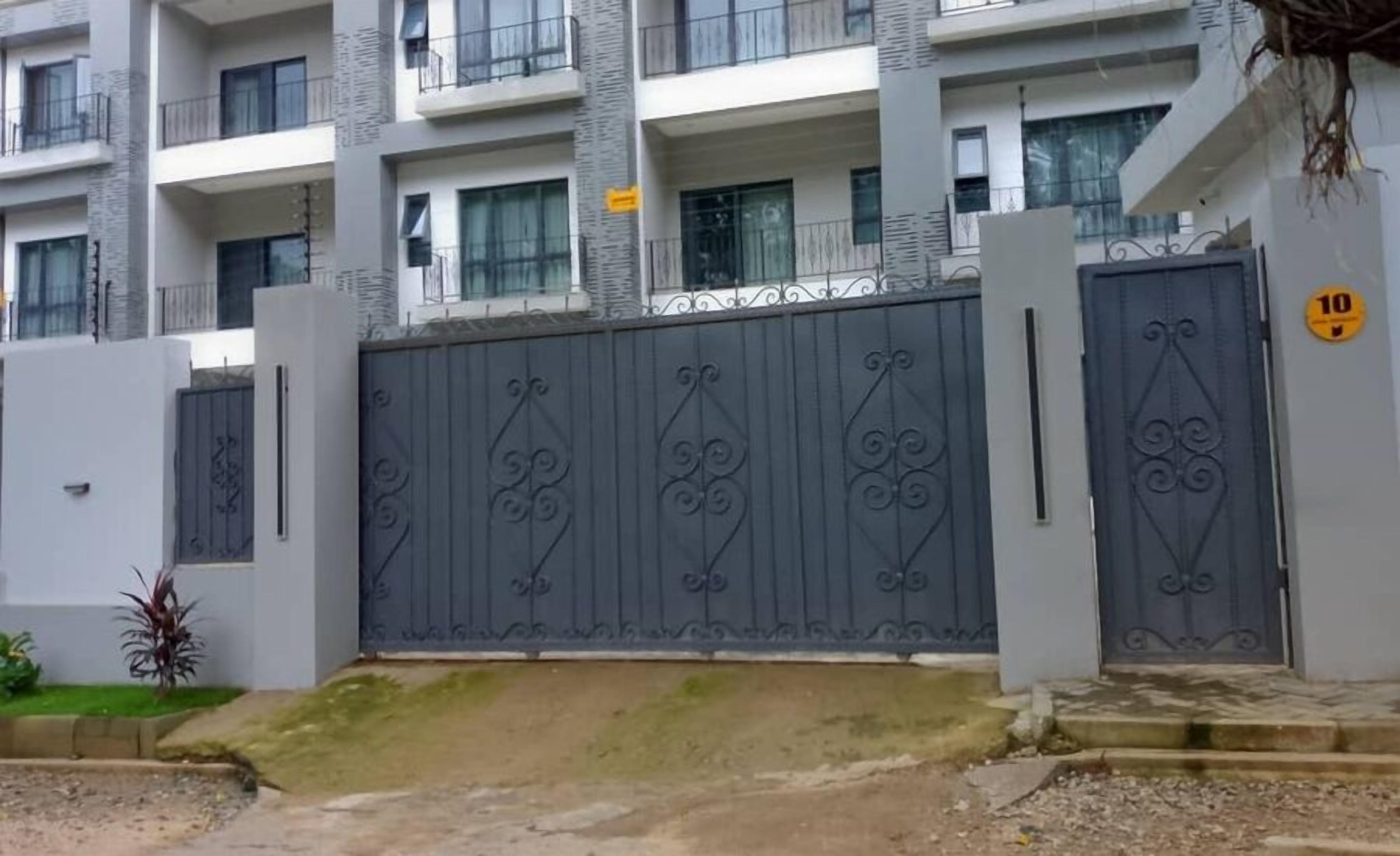 A gated entrance to a multi-story residential building with a grey metal gate and a number '10' sign.