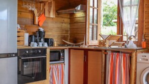 Una cocina compacta con paredes de madera, estufa, horno, microondas y lavadora.