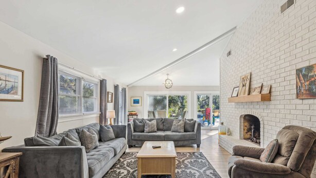 A spacious living room with a gray sofa set, a wooden coffee table, and a patterned rug.