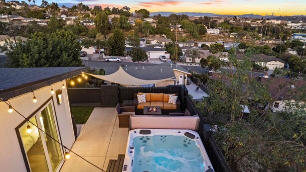 A rooftop patio with a hot tub, outdoor seating, and string lights.
