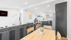 A modern kitchen with white cabinets, a black refrigerator, and a dining area with a wooden table and chairs.