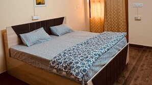 A bedroom with a wooden bed, a ceiling fan, and a window with curtains. - Luxe Heaven (Jaipur)