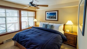 Ein Schlafzimmer mit einem großen Bett, zwei Nachttischlampen, einem Deckenventilator und einem gerahmten Bild an der Wand.