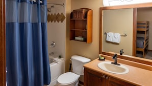 Ein Badezimmer mit einer Badewanne, Toilette, Waschbecken und einem Spiegel.
