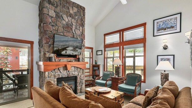 Una sala de estar acogedora con chimenea de piedra, asientos cómodos y ventanas amplias.
