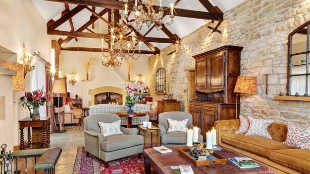 Un salón acogedor con pared de piedra, muebles de madera y una araña.