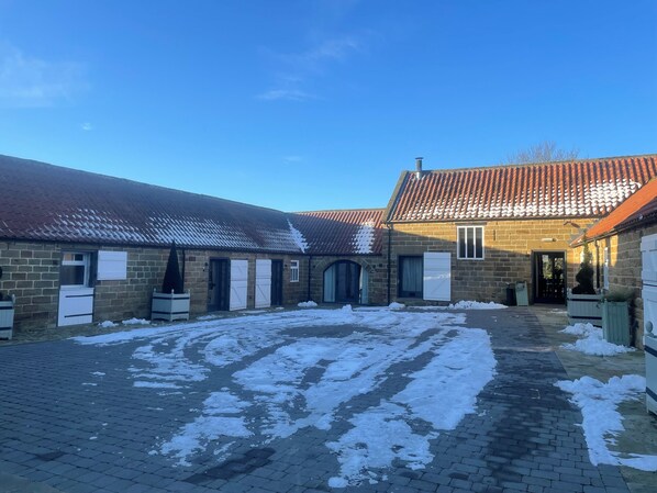 Un cortile con edifici in mattoni, un vialetto lastricato e neve a terra.