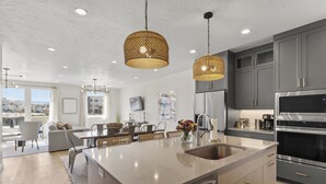 Una cocina moderna con una isla grande, electrodomésticos de acero inoxidable e iluminación colgante.