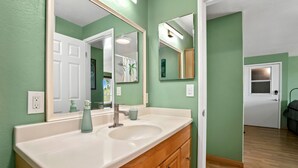 A bathroom with a white sink, wooden vanity, and two mirrors. - Kauai Hale Kahanalu 8 2 Bedroom Condo (Koloa)