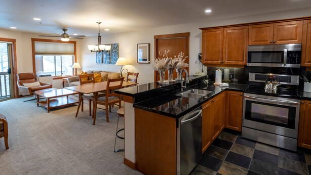 A modern kitchen with wooden cabinets, stainless steel appliances, and a checkered floor.