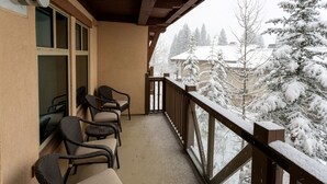 A covered balcony with wicker chairs and a view of snow-covered trees.