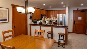 A modern kitchen with wooden cabinets, stainless steel appliances, and a dining area with a wooden table and chairs.