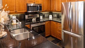A modern kitchen with wooden cabinets, stainless steel appliances, a granite countertop, and a sink.