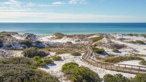 A sandy beach with a wooden boardwalk curving through the dunes, leading to the ocean. - Watersound Beach! With Carriage House, Private Pool, LSV/Golf Cart, & 4 Bikes! (Watersound)