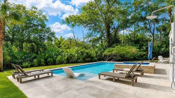 Une piscine avec des chaises longues et une terrasse en pierre.