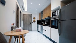 Een moderne keuken met een inbouwoven, magnetron en koelkast. Er staat een eettafel met stoelen en een bloemenvaas.