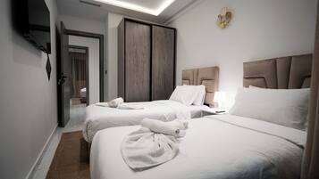 A hotel room with two beds, a wardrobe, a flat-screen TV, and a ceiling light.