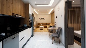Een moderne keuken met een vaatwasser, een eethoek met een tafel en stoelen, een bank en een zithoek met een salontafel.