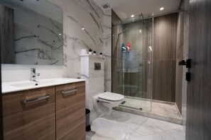Bathroom features a large mirror, sink, and separate shower area with a glass door.