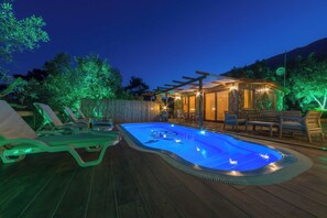 A swimming pool with lounge chairs and a covered seating area at dusk. - Ceren Villa Akyaka Daily Weekly Rentals (Ula)
