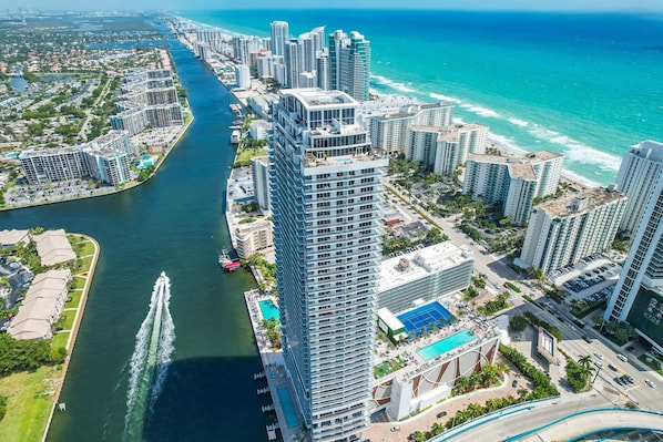 A high-rise hotel with a view of the ocean and a marina.