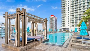 A rooftop pool area with wooden pergolas, lounge chairs, and umbrellas. - 2BR Ocean Penthouse: Private Terrace & Hot Tub (Hollywood)