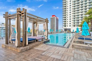 A rooftop pool area with wooden pergolas, lounge chairs, and umbrellas. - 2BR Ocean Penthouse: Private Terrace & Hot Tub (Hollywood)