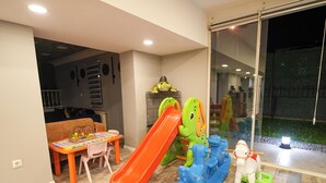 A play area with a slide, a frog-shaped climbing structure, and a horse-shaped ride-on toy. - Yeşil Panjurlu Villa Otel (Bursa)