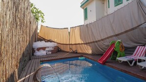 A swimming pool with a slide, lounge chairs, and a covered deck area. - Yeşil Panjurlu Villa Otel (Bursa)